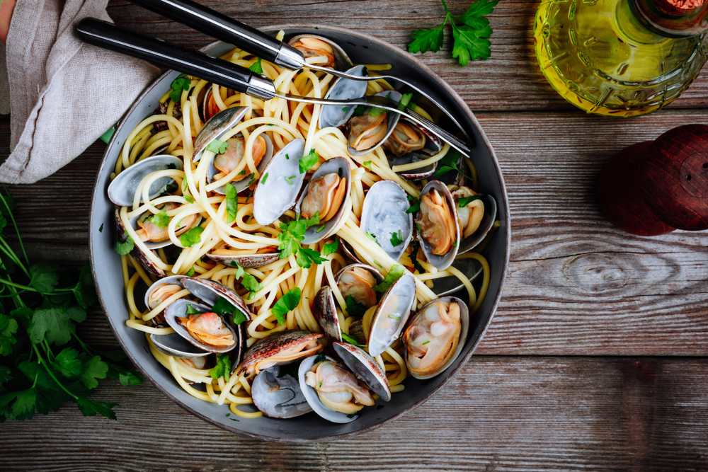 Traditional italian seafood pasta with clams Spaghetti alle Vongole in the pan on wooden background