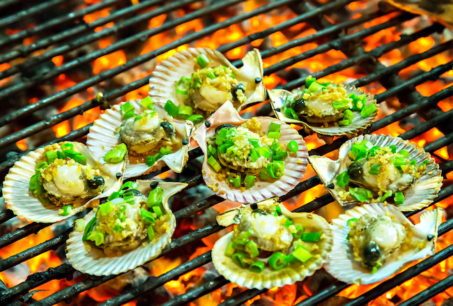 Grilling oysters food on the flaming grill. Summer barbecue concept seafood.