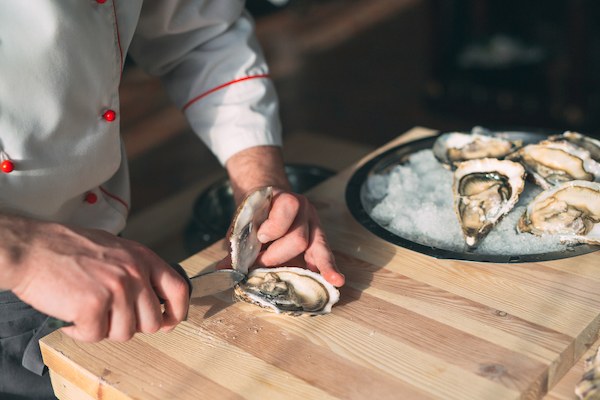 Opening the hollow and flat oysters. Chef opens oysters in the restaurant